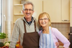 a senior couple standing in their apartment kitchen