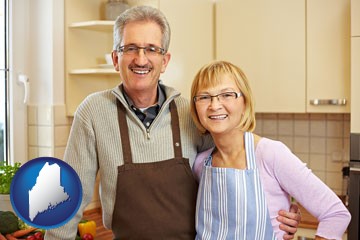a senior couple standing in their apartment kitchen - with Maine icon